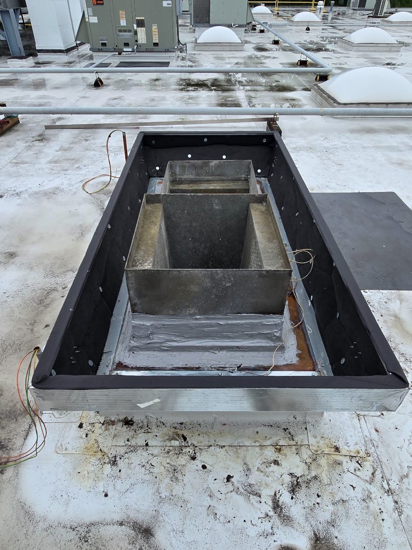 An open rectangular roof penetration with the old duct removed and the curb exposed