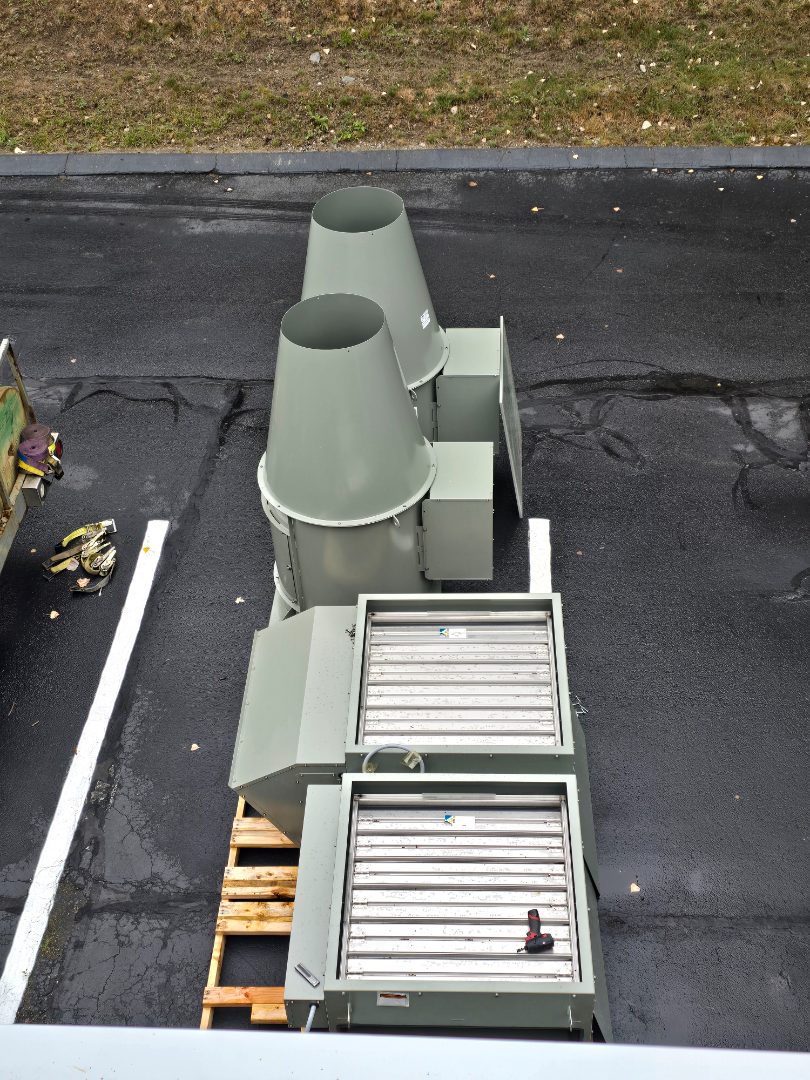 New exhaust fans and filter sections staged on dunnage in a parking lot