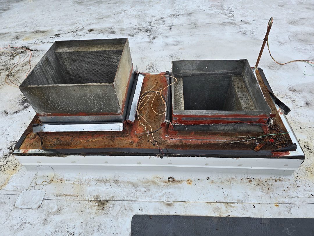 Two corroded roof curbs with the old exhaust ductwork cut away and wiring exposed