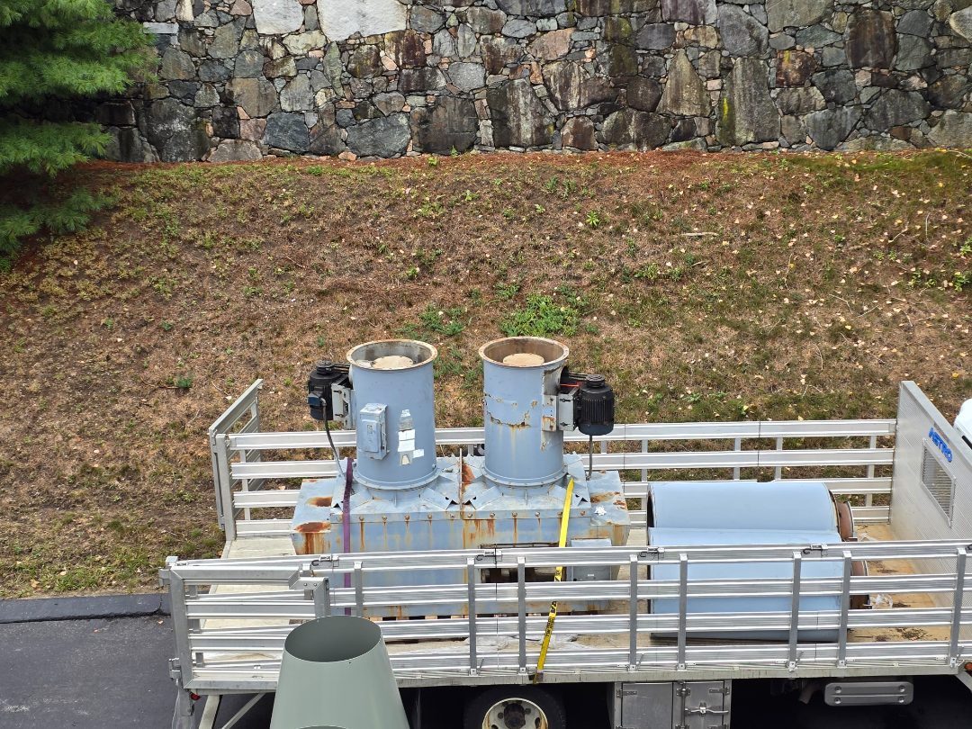 Two removed exhaust fans and their motors loaded on a flatbed truck